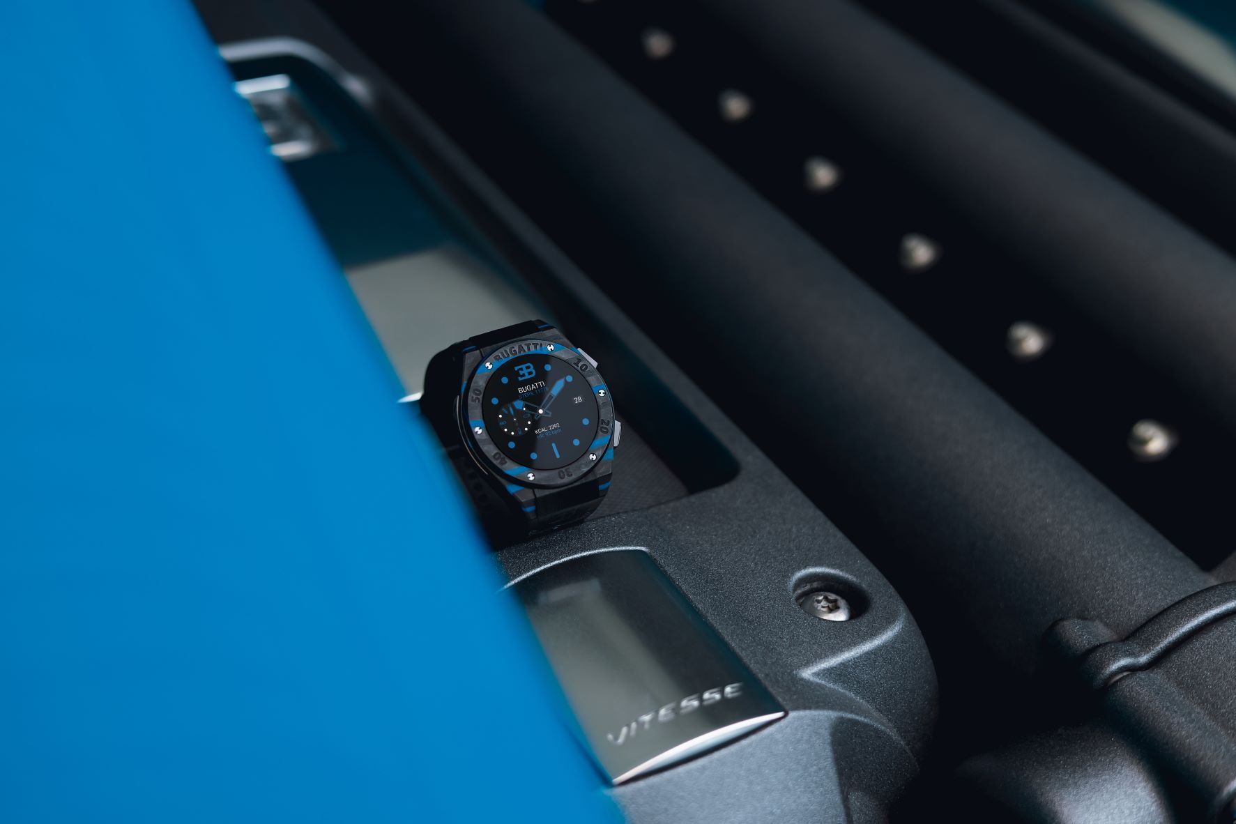 Bugatti Carbone limited edition smartwatch on the engine bay of a Bugatti Veyron hypercar in blue