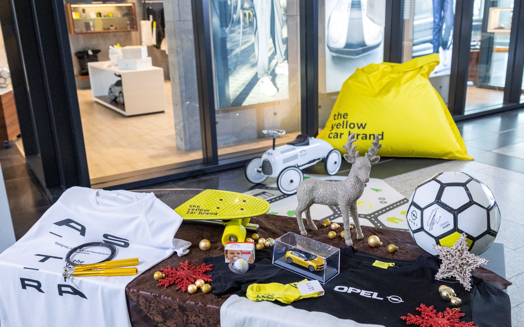 Items from Opel's brand collection on display including a t-shirt, football, model cars and more.