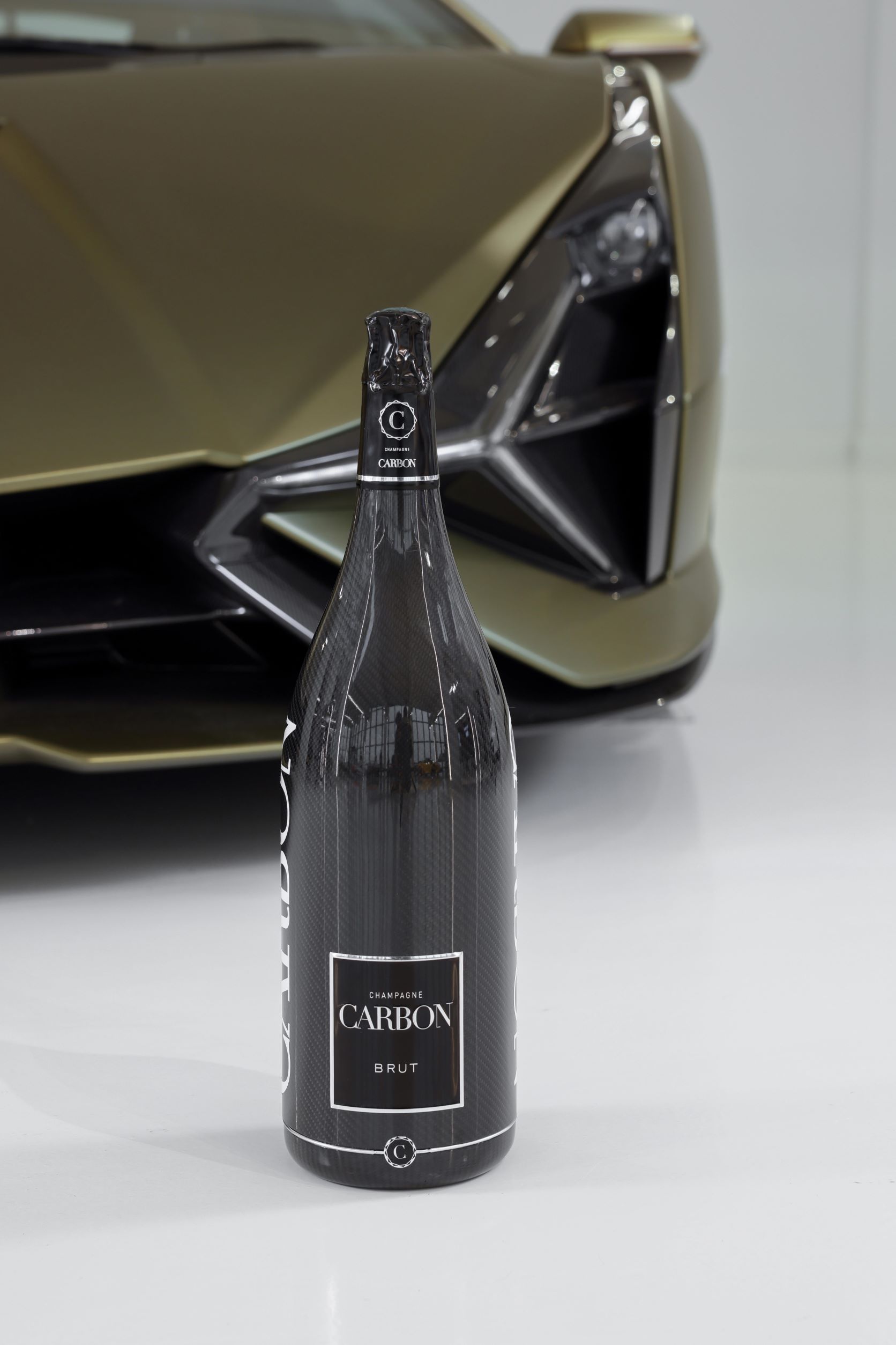 A green colour bottle of Champagne Carbon presented in front of a Lamborghini Sian