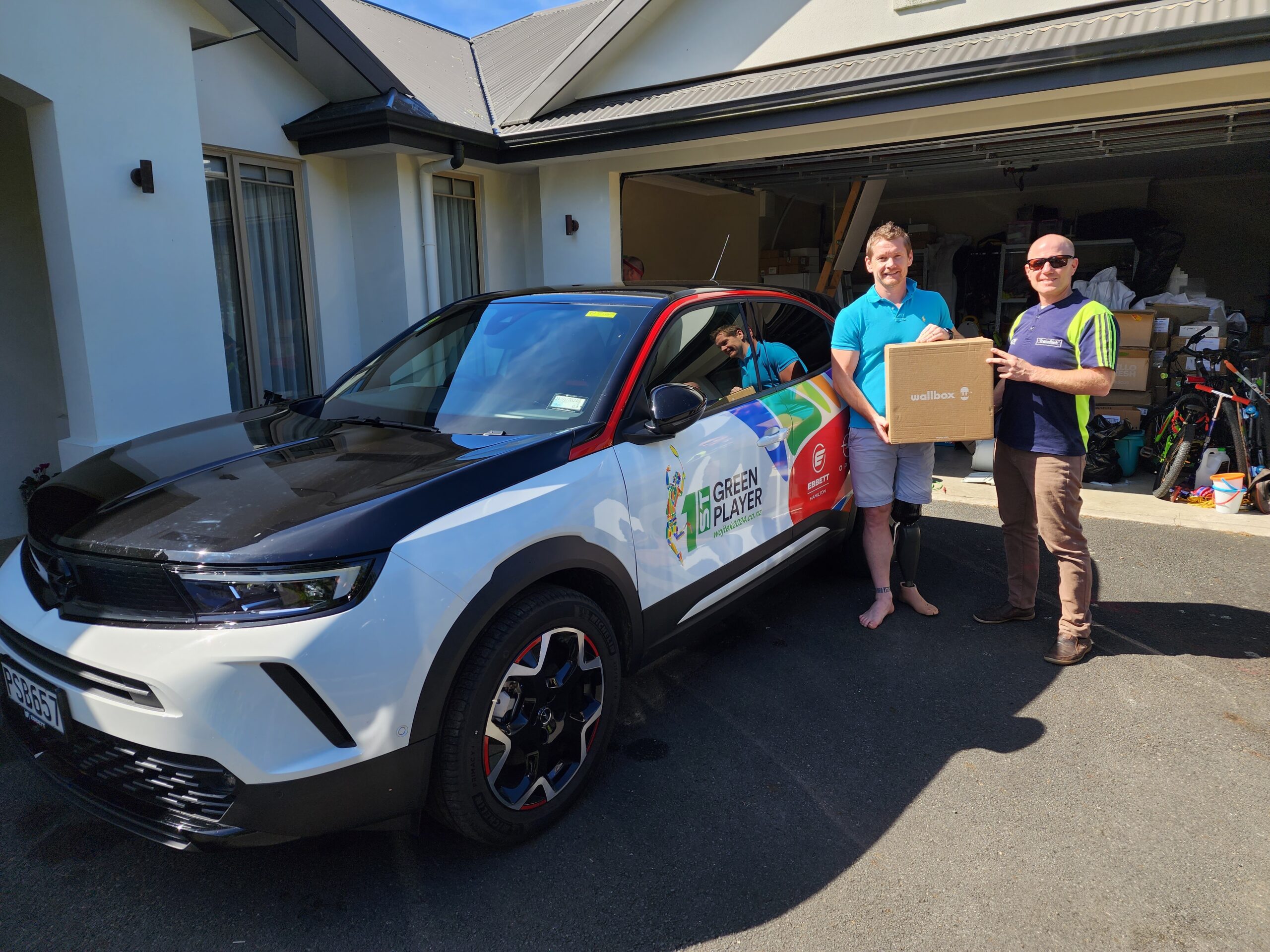Paralympian Wojtek Czyz with Opel Mokka-e EV and Wallbox Pulsar Plus Eco-Smart charger in New Zealand.