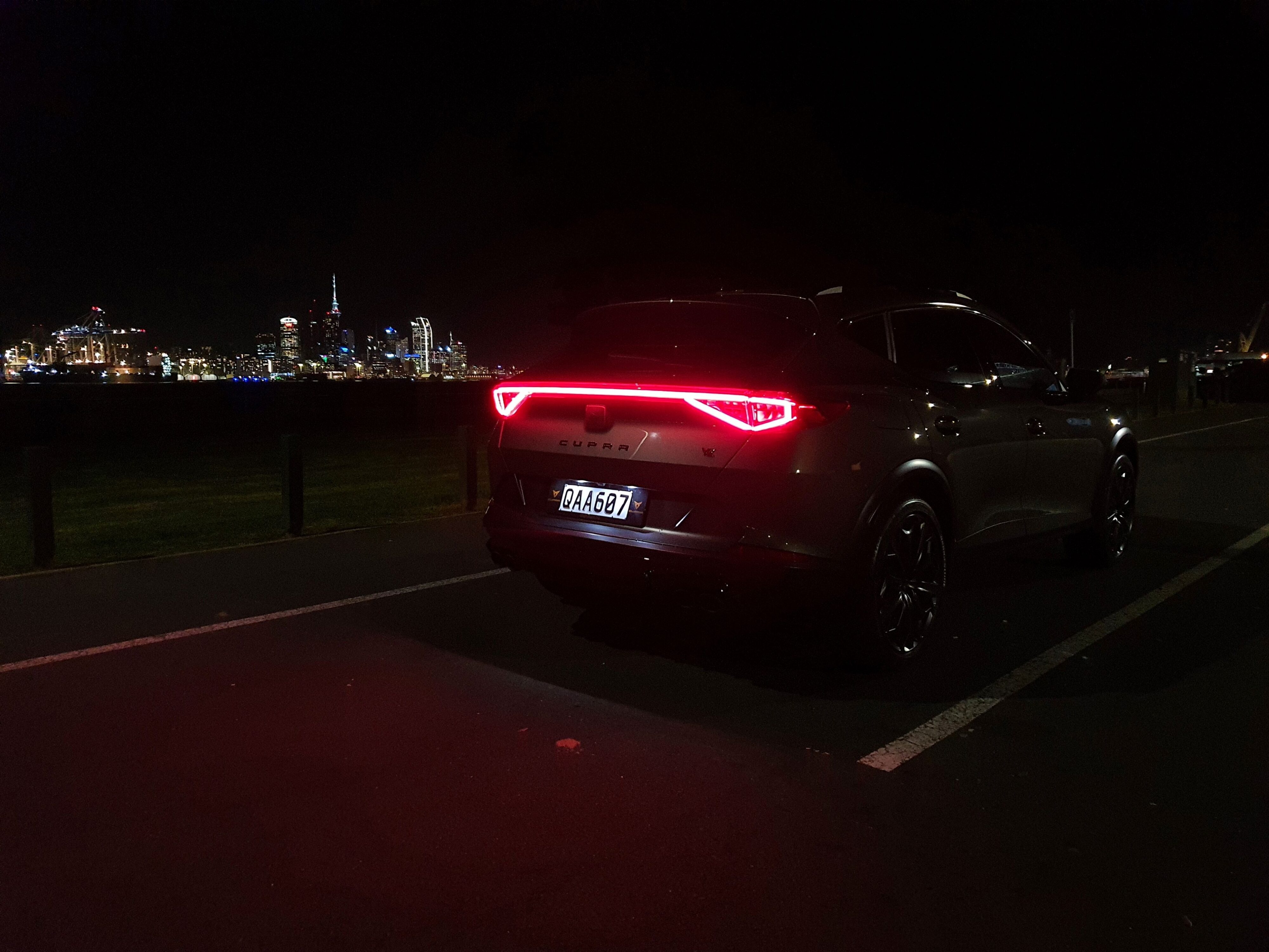 A night photo of a Cupra Formentor VZ Tribe Edition with Auckland City in the background.