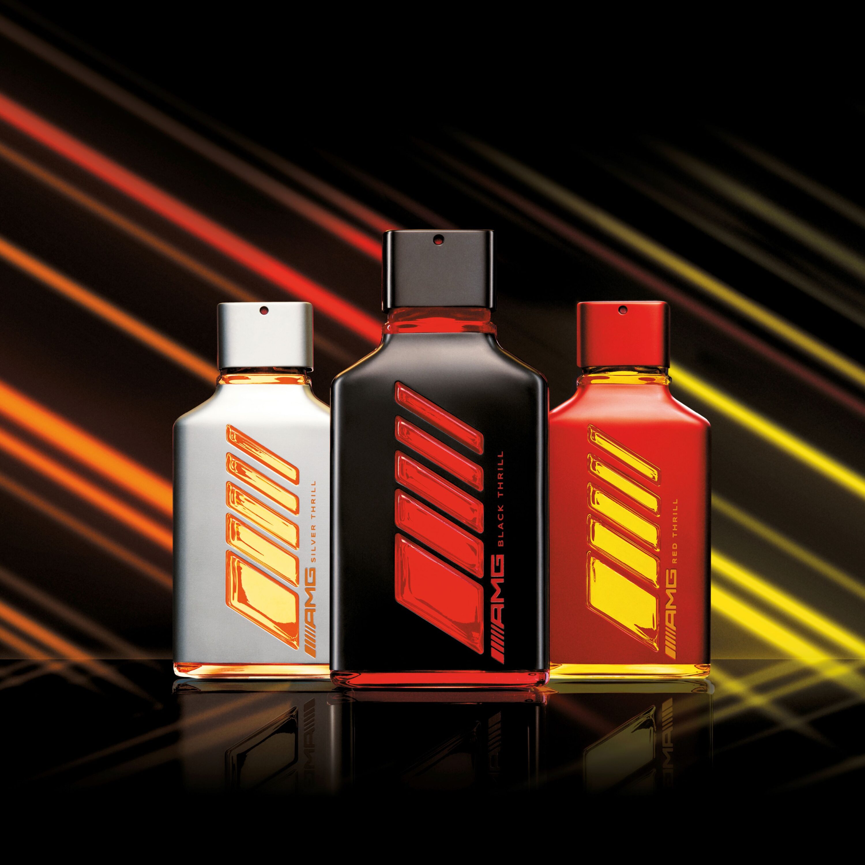 Promotional photo of three Mercedes-AMG fragrance bottles. One in silver, black and red respectively.