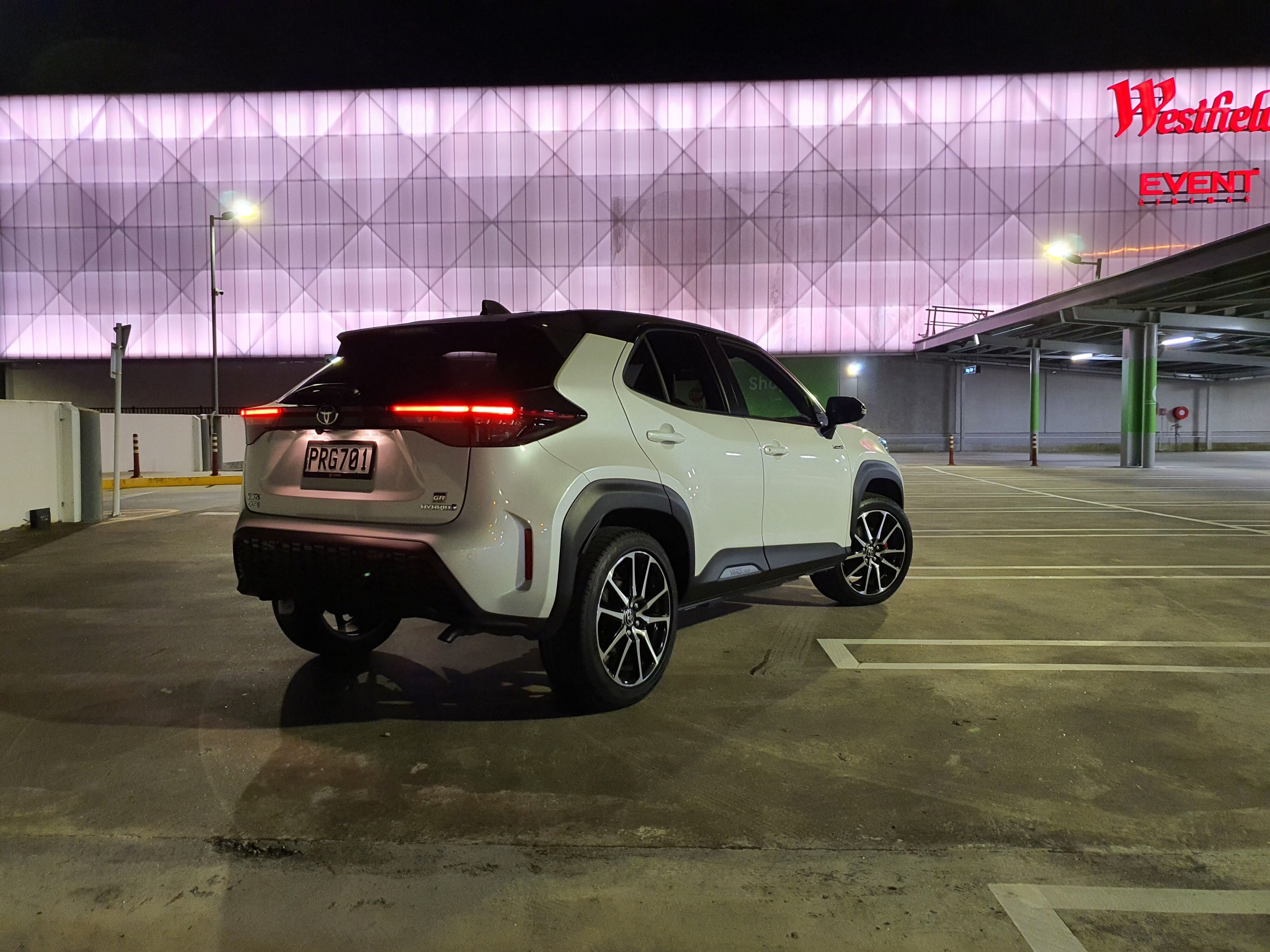 Rear three quarters view of a 2023 Toyota Yaris Cross GR Sport in a white and black colour scheme on the rooftop of a mall.