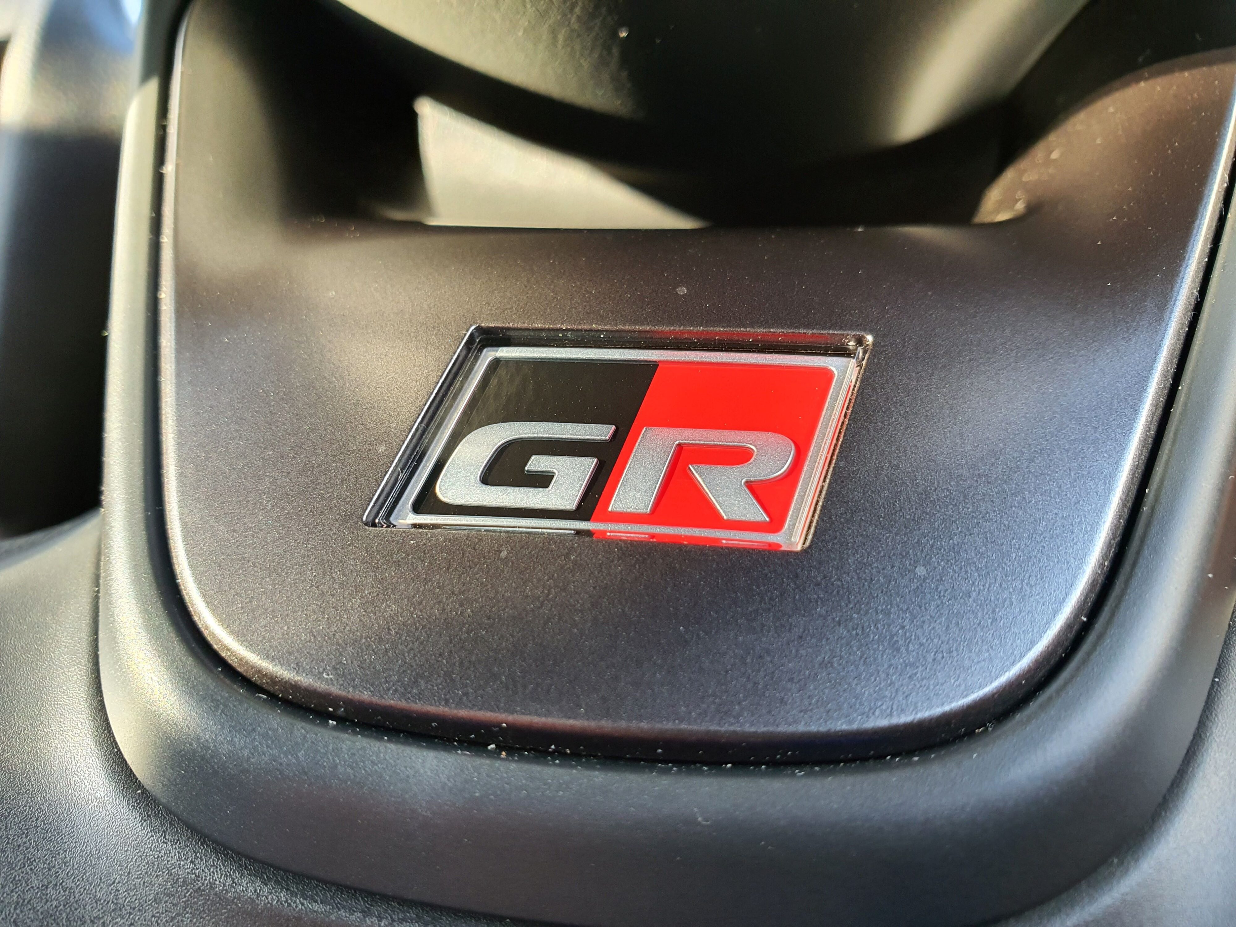 A close-up of the GR badge on the steering wheel of a 2023 Toyota Yaris Cross GR Sport.