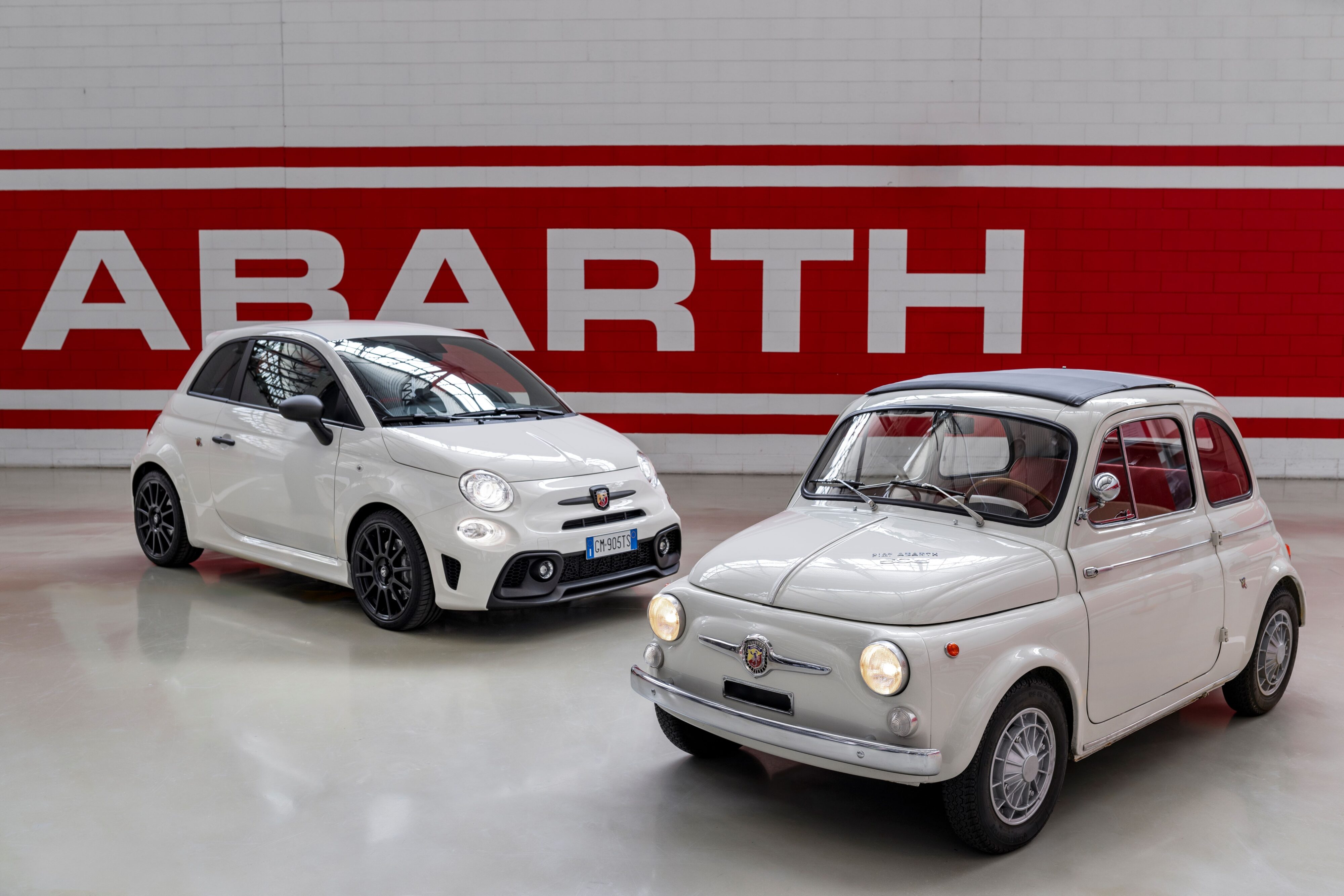 A photo of two Abarth 595s together, one old and one new. Both in white.
