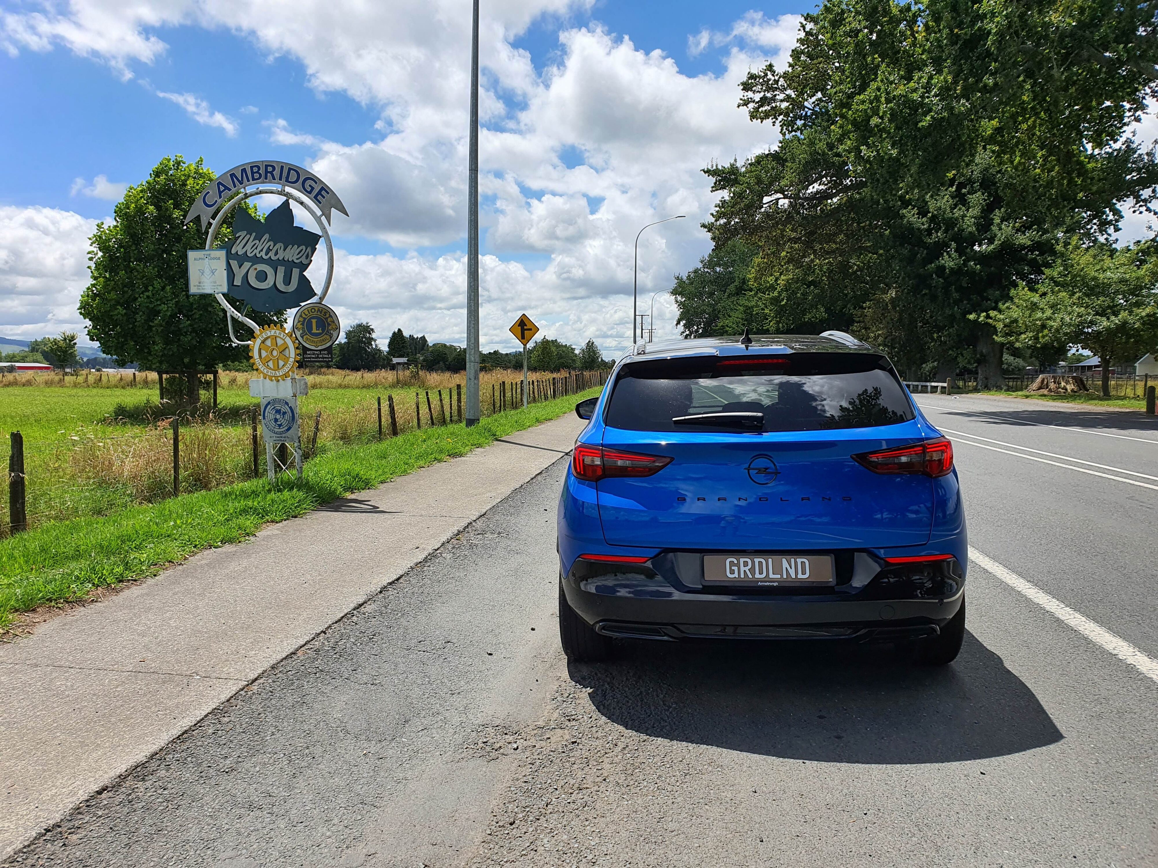 Photo of a Cobalt Blue Opel Grandland SRi with a sign signifying Cambridge Town, Waikato, New Zealand.