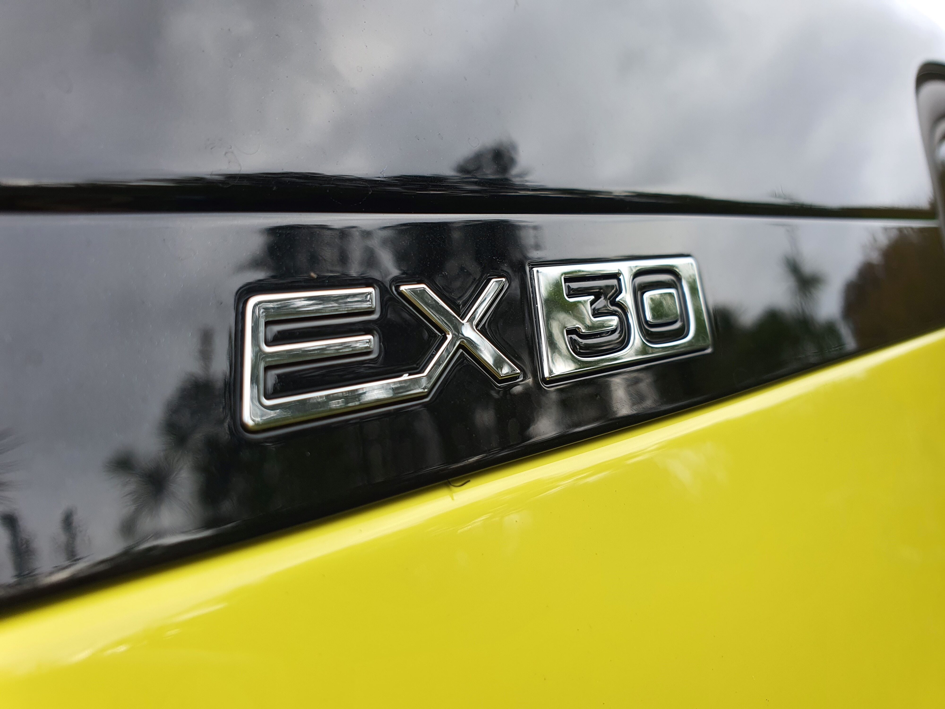 EX30 badge in chrome on a black background on a 2024 Volvo EX30 in Moss Yellow.