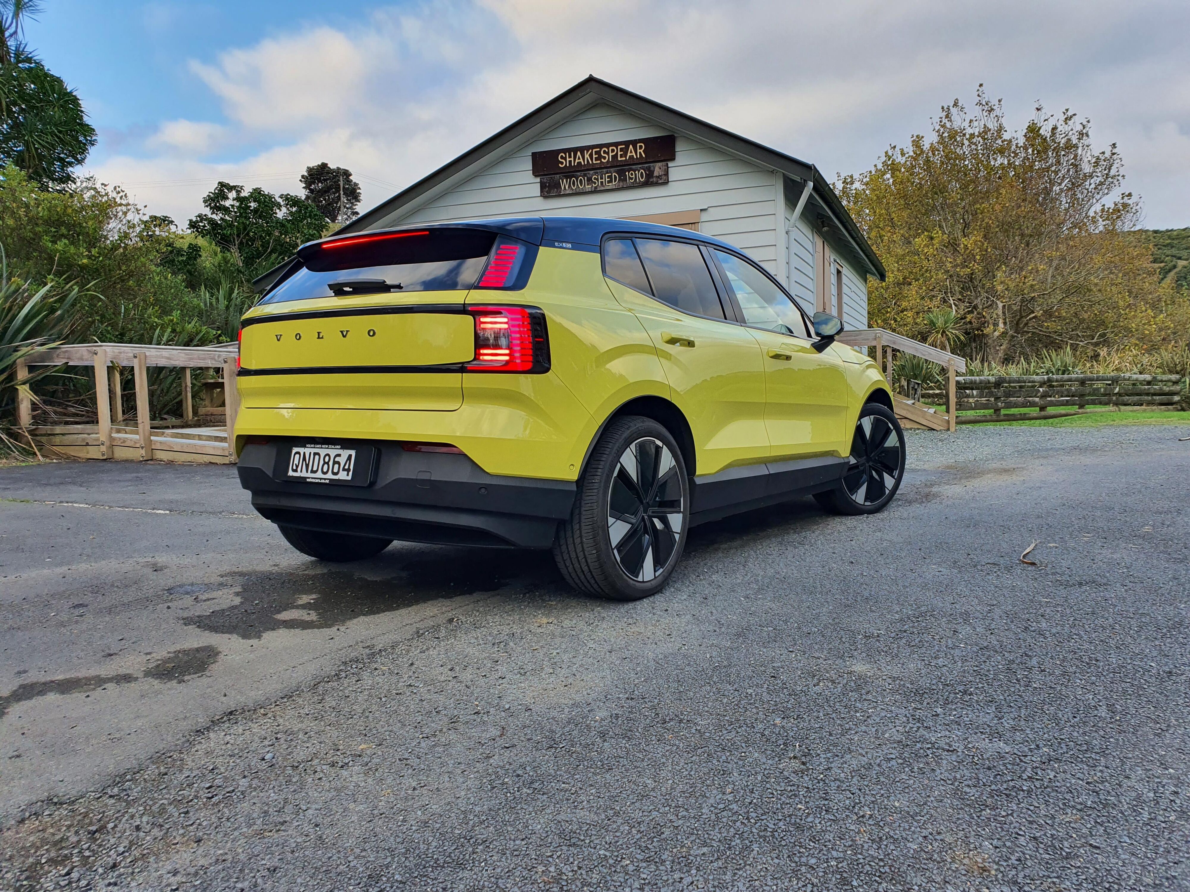 Rear three quarters view of a 2024 Volvo EX30 in Moss Yellow.