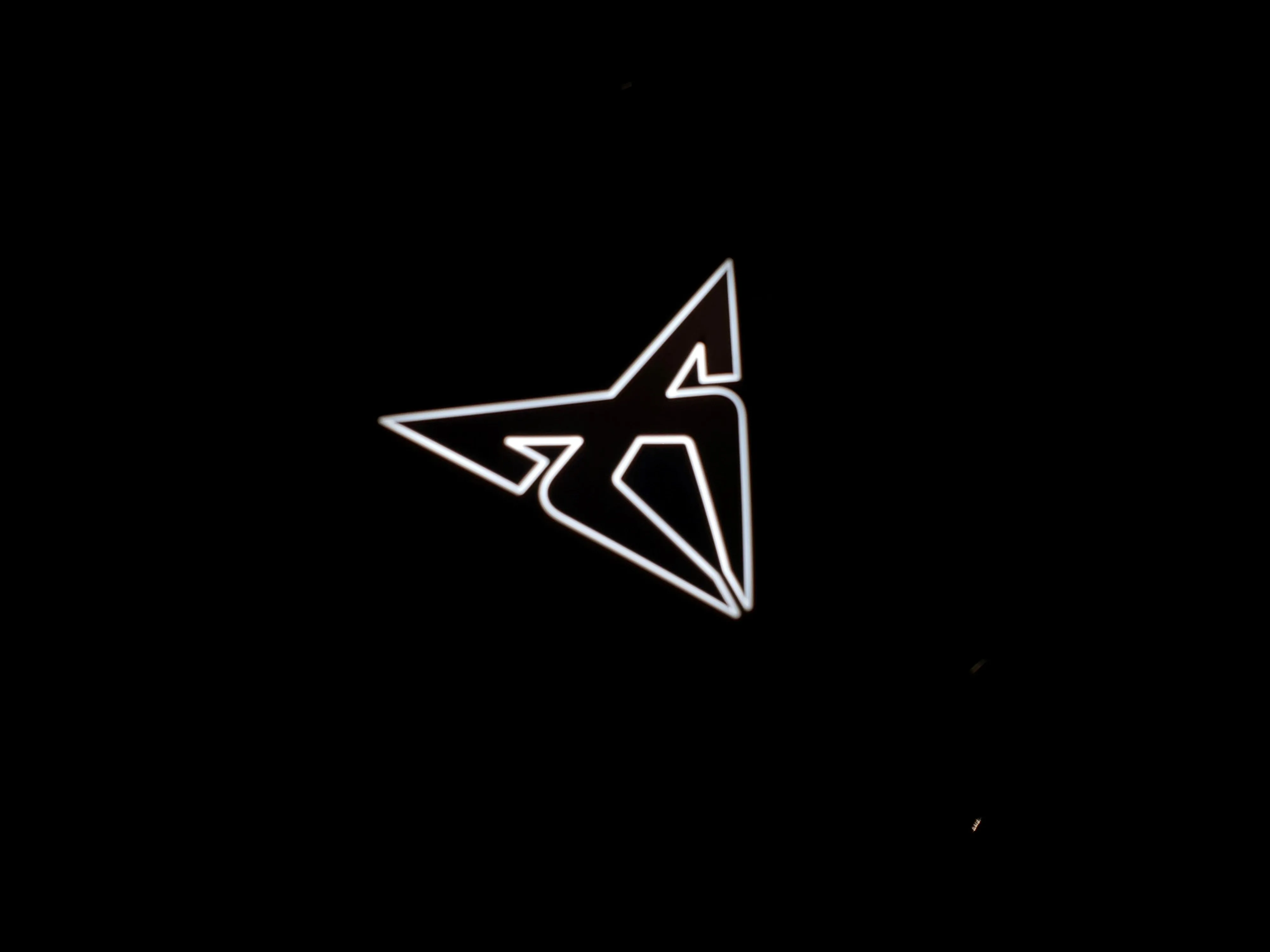 View of the backlit Cupra badge on the front of a 2025 Cupra Tavascan VZ in Tavascan Blue.