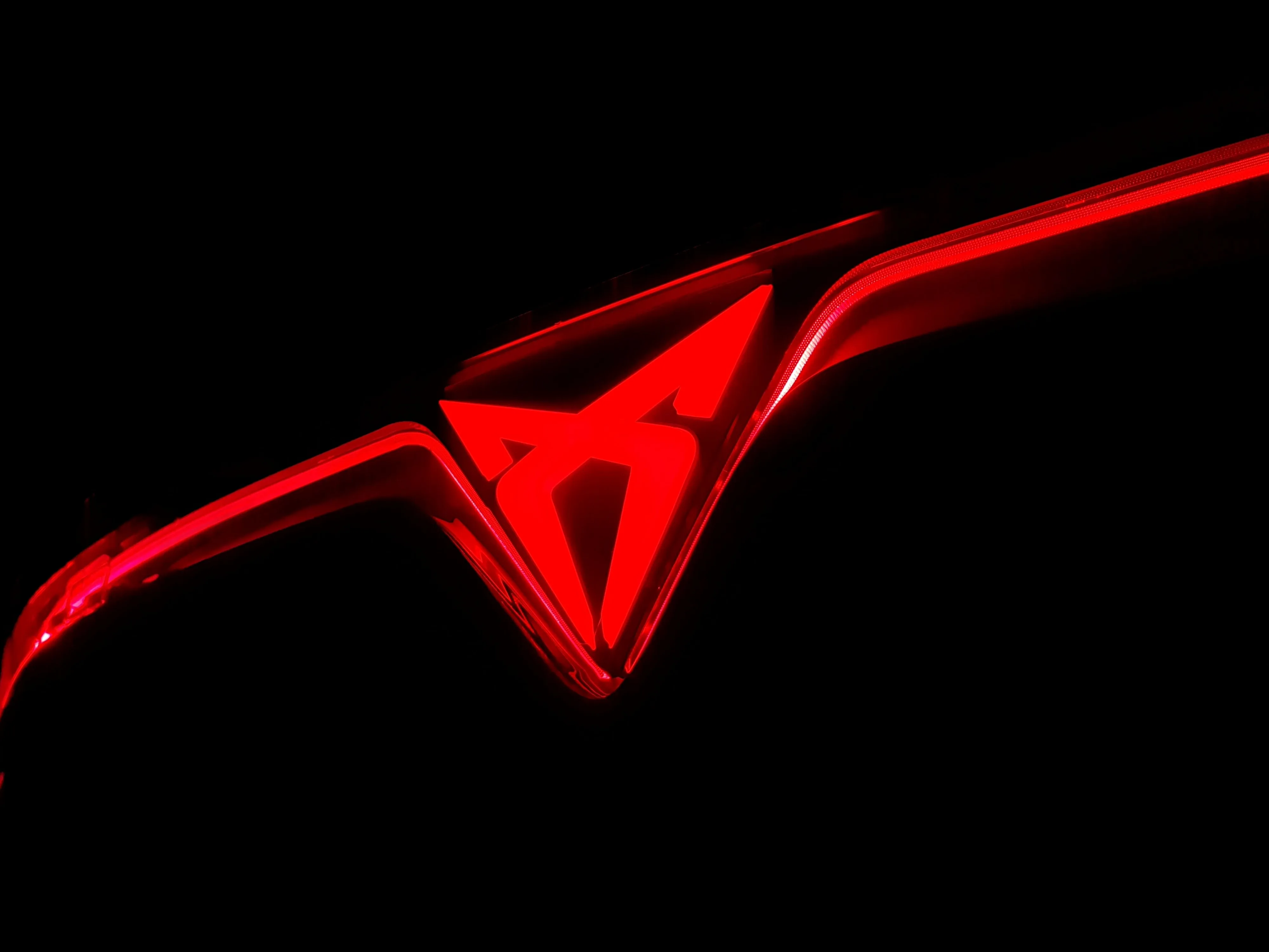 View of the illuminated Cupra badge on the rear of a 2025 Cupra Tavascan VZ in Tavascan Blue.