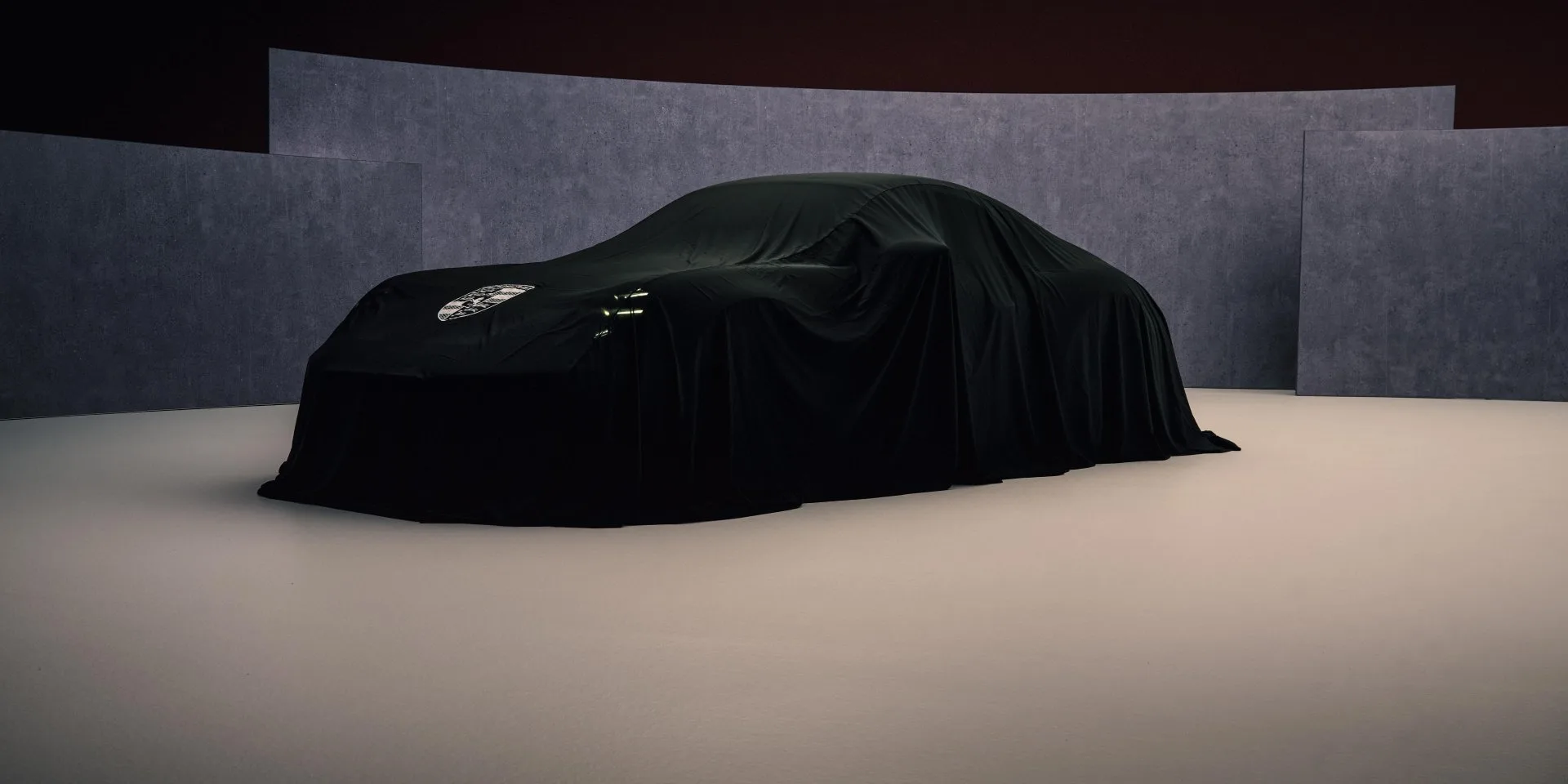 A teaser image of the new Porsche 911 under a black car cover.