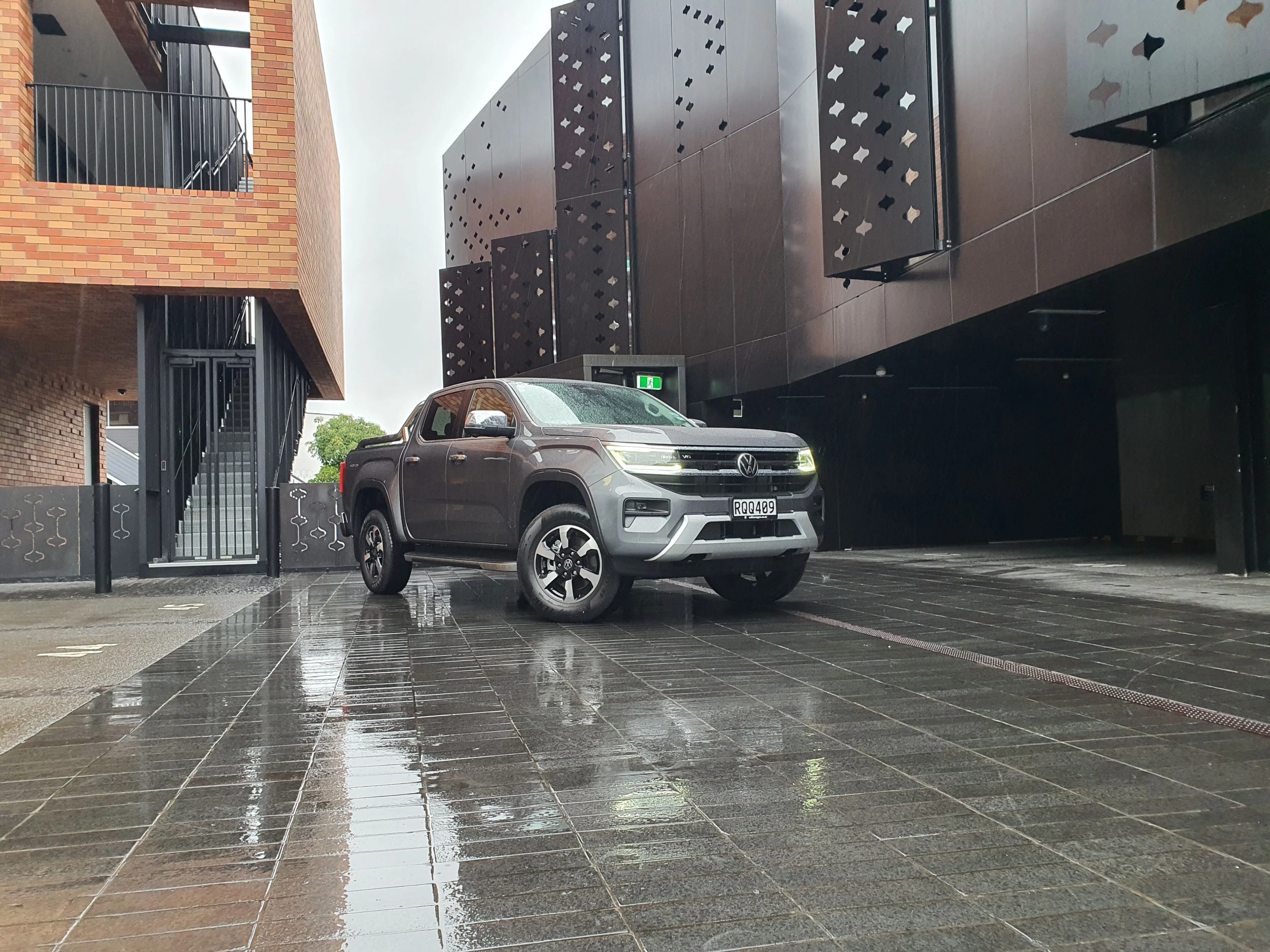Front three quarters view of a 2026 Volkswagen Amarok V6 Style in Carbonite Grey with an urban background.