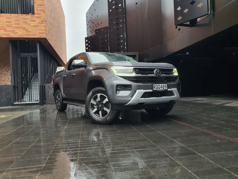 Close up front three quarters view of a 2026 Volkswagen Amarok V6 Style in Carbonite Grey with an urban background.